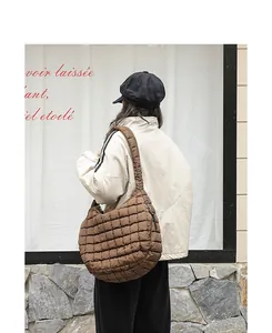 Detail view of large brown quilted nylon hobo bag carried by model in urban street style