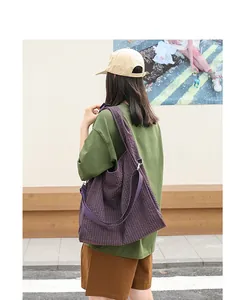 Detalle de un bolso tote de lona a cuadros morados llevado por una modelo con estilo.