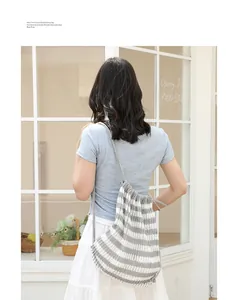 Vista trasera de una modelo con una mochila de punto a rayas con cordón de estilo japonés