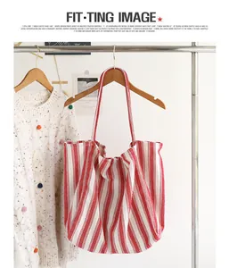 Borsa tote in tela a righe rosse e bianche appesa a un appendiabiti per l'esposizione