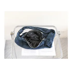 Detail view of the black lining inside a blue denim dumpling bag with knotted strap