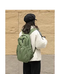 Modelo con mochila de nailon verde plisada, vista trasera que muestra el gran diseño