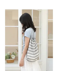 Elegante mochila de punto a rayas con cordón mostrada en una modelo en exteriores