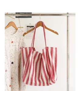 Borsa tote in tela a righe rosse e bianche appesa a una gruccia di legno in stile casual