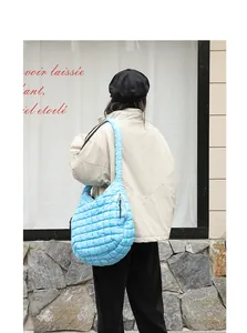 Detail of sky blue quilted nylon hobo bag carried by a model in a street setting