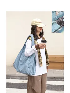 Foto de estilo de vida de un gran bolso tote azul con textura de burbujas en modelo.