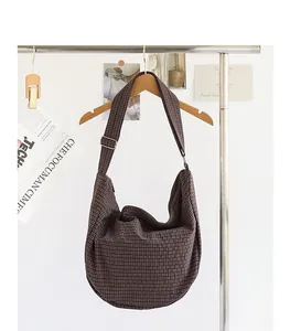 Primer plano de un bolso bandolera de lona a cuadros de estilo japonés en una percha de madera.