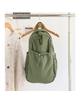 Detalle de mochila de nailon verde oliva con cordón en un entorno de estilo de vida.