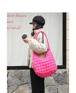 Close-up of bright pink quilted nylon puffer hobo bag on model's shoulder