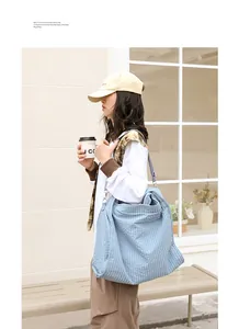 Vista de estilo de vida de una modelo con un gran bolso tote de lona a cuadros azul claro