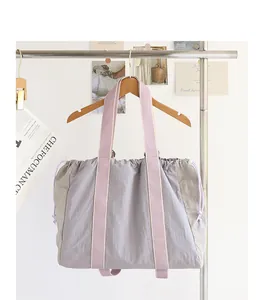 Bolso tote grande de nailon con bloques de color y cordón colgado de una percha de madera