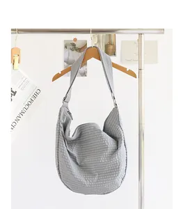 Bolso dumpling de lona a cuadros grises de estilo japonés colgado de una percha de madera
