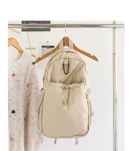 Mochila de nailon beige de estilo japonés colgada de una percha de madera con cordón