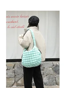 Lifestyle view of a light green quilted puffy nylon shoulder bag carried by a model.
