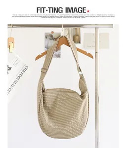 Vista detallada de un bolso de lona a cuadros beige colgado en un perchero de madera