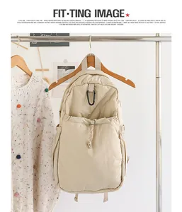 Mochila informal de nailon beige con cordón colgada en un perchero de madera de estilo
