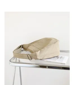 Detalle de cerca de un bolso dumpling de lona a cuadros beige en una mesa.