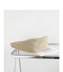 Vista detallada de un bolso de lona a cuadros beige estilo japonés sobre mesa de cristal.