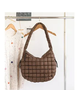 Close-up view of a brown quilted nylon hobo bag hanging on a wooden hanger in a cozy setting