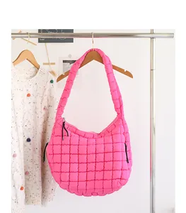 Detailed view of a trendy hot pink quilted nylon shoulder bag with grid pattern hanging on a rack