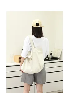 Casual canvas tote bag with letter print shown on a model in a minimalist room setting.