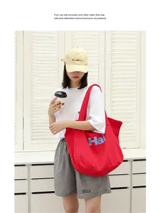 Casual red canvas tote bag with Hai letter print carried by a model in a lifestyle shot