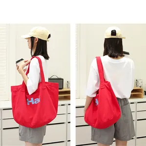 Vibrant red canvas tote bag with letter print shown from two angles on a female model