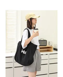 Woman carrying black canvas tote bag with white letter print in a lifestyle setting