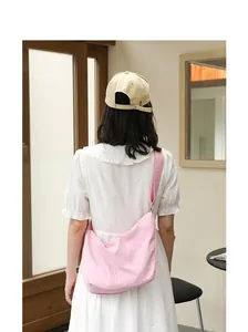 Detailed back view of a stylish pink pleated nylon crossbody bag for women in white dress
