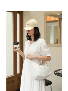 Asian model wearing a stylish minimalist white pleated nylon crossbody bag in a cafe