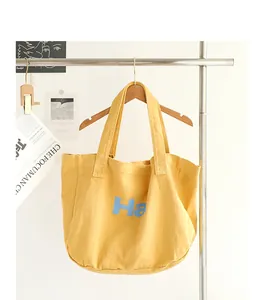 Detailed view of the yellow washed canvas tote bag with light blue Ha print
