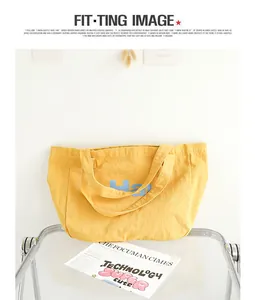 Detailed view of a yellow washed canvas tote bag featuring blue letter print details