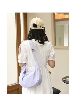 Detail of a lavender crinkled nylon crescent crossbody bag worn by a model in a white dress