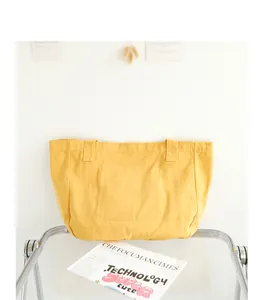 Yellow canvas tote bag shown in a minimalist aesthetic lifestyle setting on a glass table