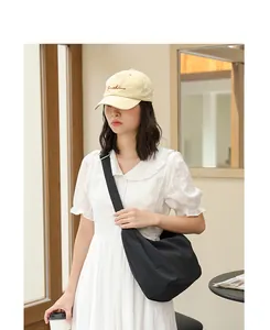 Black pleated nylon crossbody bag for women styled with a white summer dress and cap
