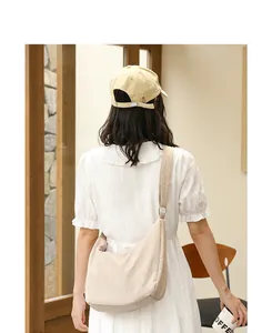 Rear view of model with beige wrinkled fabric crossbody bag in minimalist aesthetic