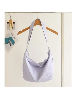 Close-up of a light purple pleated nylon crossbody bag with textured fabric detail