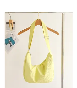 Detailed view of yellow pleated nylon hobo bag hanging on a wooden hanger accessory