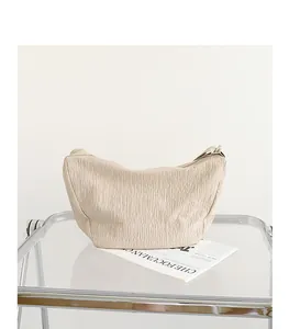 Minimalist beige crinkled nylon shoulder bag with stylish pleated texture in a scene