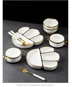 High-quality close-up of white ceramic divided plates with elegant gold rims and cutlery.