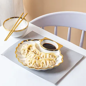 Plato de cerámica blanca para dumplings con borde dorado y salsera integrada en mesa