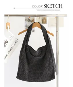Gran bolso hobo de lona a cuadros colgado de una percha de madera en un estudio limpio.