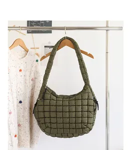 Detail of olive green quilted nylon hobo bag with grid padded design hanging on rack