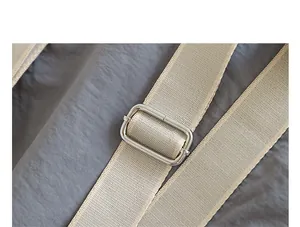 Detalle macro de la hebilla metálica ajustable y la correa beige en un bolso de nailon gris