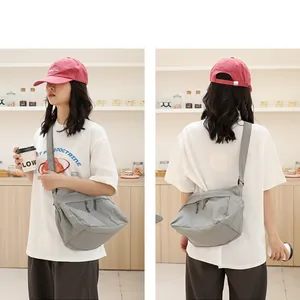 Modell trägt eine graue Nylon-Umhängetasche im japanischen Stil in einem Café-Ambiente