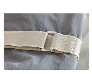Primer plano de la correa de nailon ajustable y la hebilla de metal del bolso de lona.