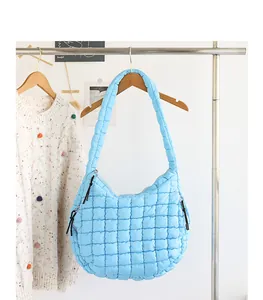 Detailed view of a light blue quilted nylon hobo bag hung on a rack with a knit sweater.