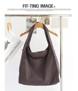 Bolso tote de lona a cuadros marrón informal colgado en una percha de madera de ropa