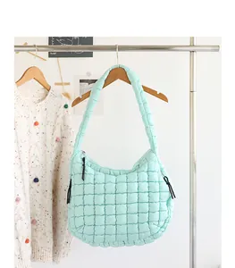 Close-up of mint green quilted nylon shoulder bag hanging on a clothing rack