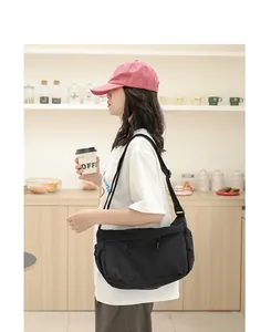 Lässige schwarze Nylon-Umhängetasche im japanischen Stil, von Model im Café getragen